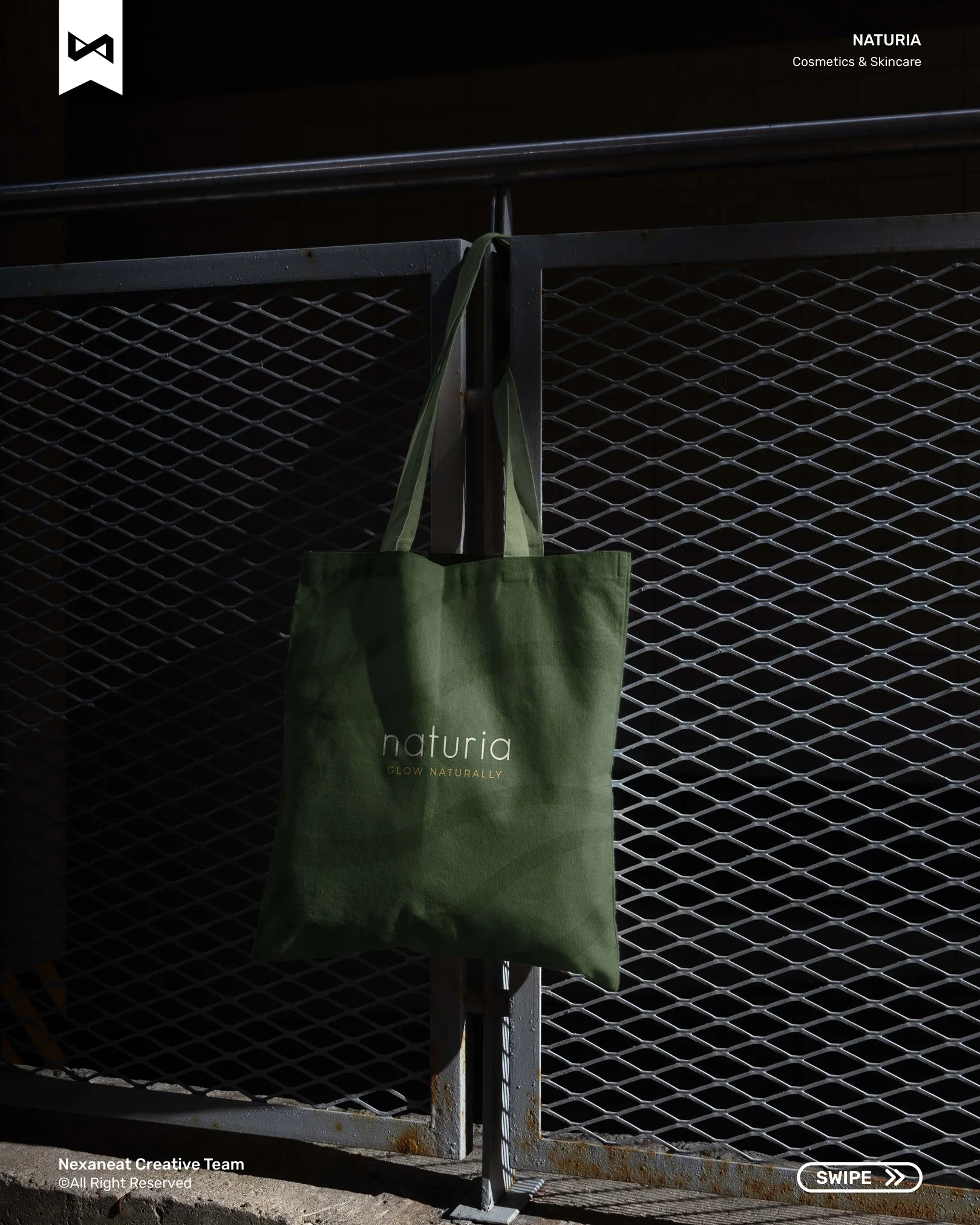 Moss-green canvas tote hanging on industrial mesh fencing